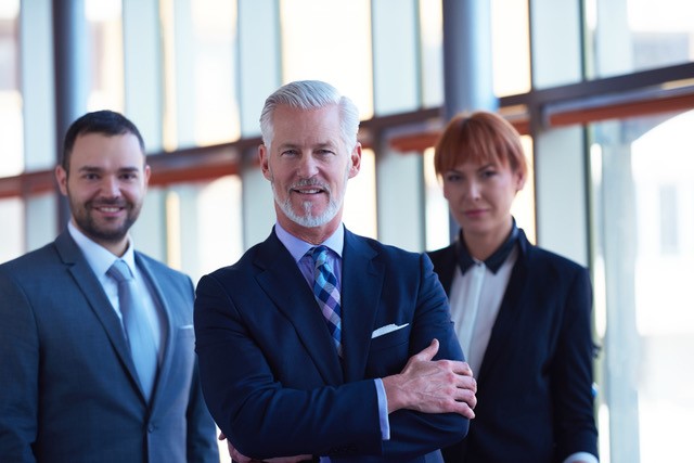 Three professionals in business attire standing confidently.